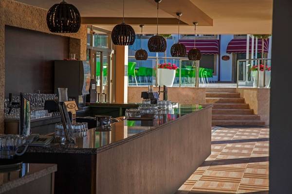 Innenansicht der Bar im Arcanus Side Resort Hotel mit Thekenbereich und Sitzbereichen draußen.