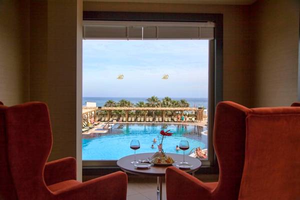 Blick vom Arcanus Side Resort Lounge auf den Pool mit roten Sesseln und Blick auf das Meer.