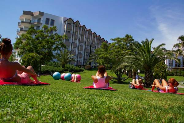 Fitnesskurs im Freien vor dem Arcanus Side Resort Hotel mit mehreren Frauen auf Matten.