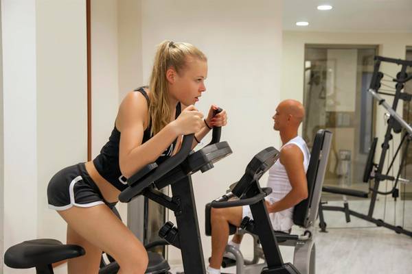 Ein Mann und eine Frau im Fitnessstudio, die auf Ellipsentrainern trainieren.