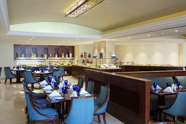 Innenansicht des Restaurants im Marjan Island Resort & Spa mit blauen Stühlen und Tischen.