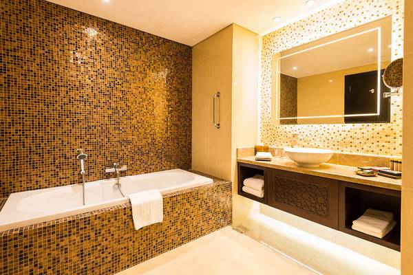 Badezimmer im Marjan Island Resort & Spa mit Badewanne, Waschbecken und Spiegel.