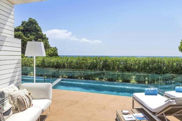 Außenbereich des ME Ibiza Hotels mit Pool, Loungemöbeln und Blick auf das Meer.