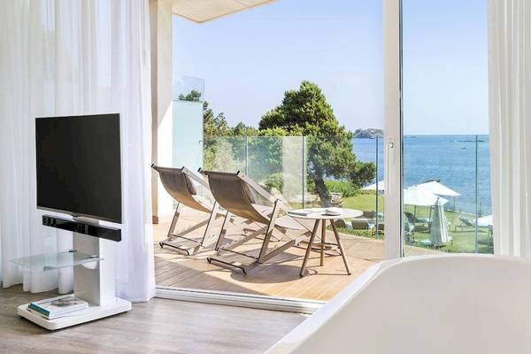 Innenansicht eines Zimmers im ME Ibiza Hotel mit Blick auf das Meer und Lounge-Stühlen.
