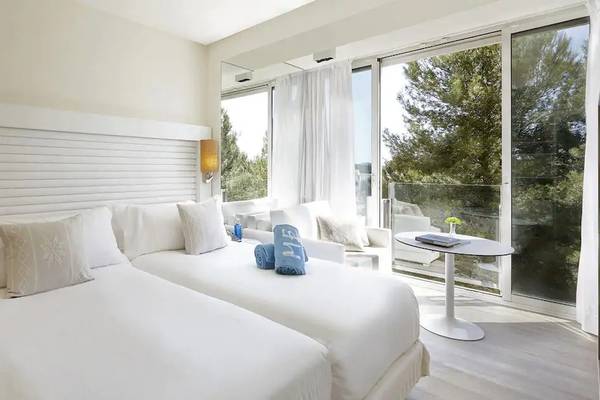 Doppelzimmer im ME Ibiza Hotel mit zwei weißen Betten, Kissen und Ausblick auf den Garten