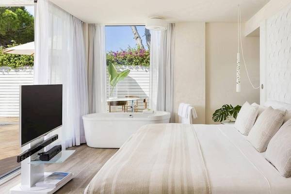 Schlafzimmer im ME Ibiza Hotel mit Badewanne, Fernseher und Pflanzen.