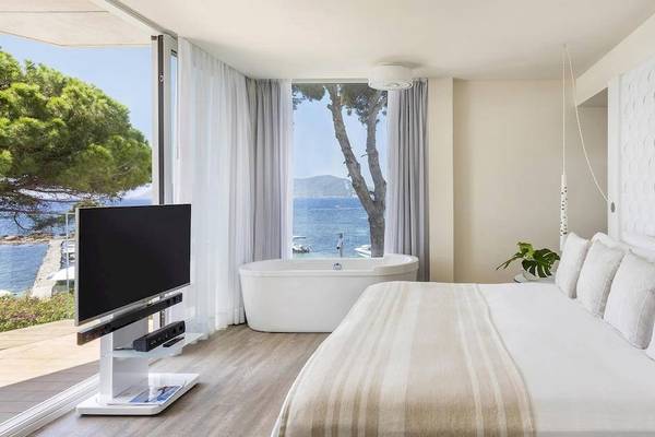 Schlafzimmer des ME Ibiza Hotels mit Blick auf das Meer und einen Baum.