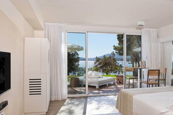 Innenansicht einer Suite im ME Ibiza Hotel mit Meerblick, Fernseher, Betten, Tisch und Stühlen.