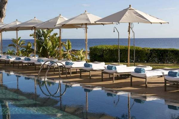 Poolbereich des ME Ibiza Hotels mit Sonnenliegen und Sonnenschirmen am Meer