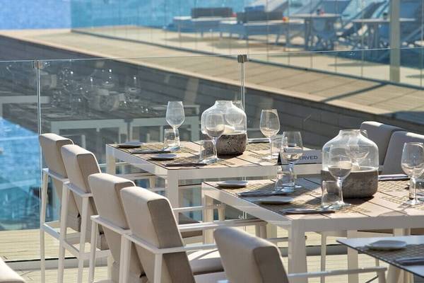 Außenterrasse des ME Ibiza Hotels mit Tisch und Gläsern vor Meerblick.