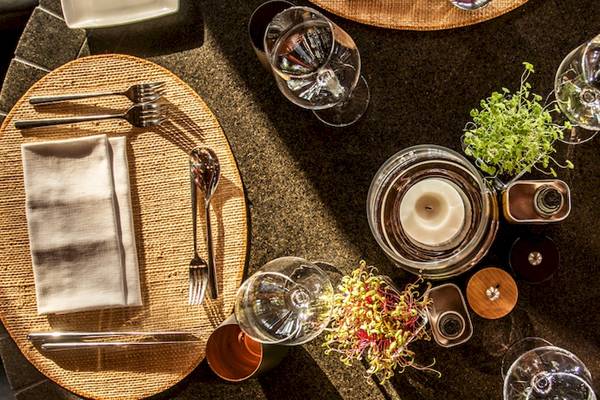 Ein Tisch im Dinarobin Beachcomber Golf Resort & Spa, mit Tellern, Besteck, Gläsern und einer Kerze dekoriert.
