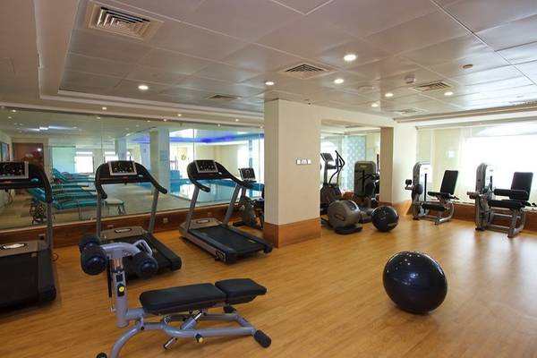 Fitnessstudio im Marjan Island Resort & Spa mit Laufbändern, Hanteln und einer großen Glaswand.
