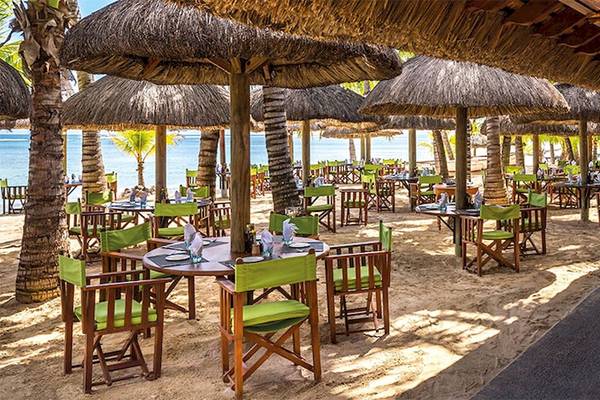 Terrasse des Dinarobin Beachcomber Golf Resort & Spa mit Tischen und Stühlen auf Sand