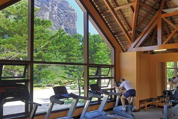 Fitnesscenter im Dinarobin Beachcomber Golf Resort & Spa mit großen Fenstern und Ausblick auf Berge