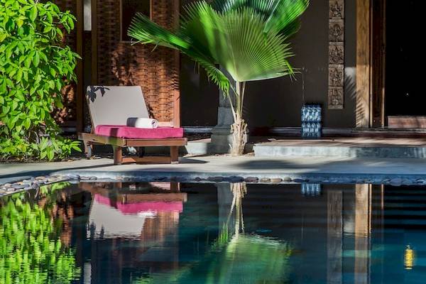 Außenbereich des Dinarobin Beachcomber Golf Resort & Spa mit Swimmingpool, Loungestühlen und Palmen.
