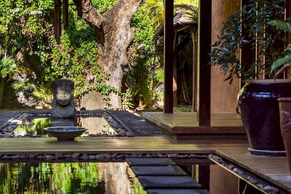 Gartenbereich des Dinarobin Beachcomber Golf Resort & Spa mit einem Wasserbrunnen, einer Statue und großen Töpfen.