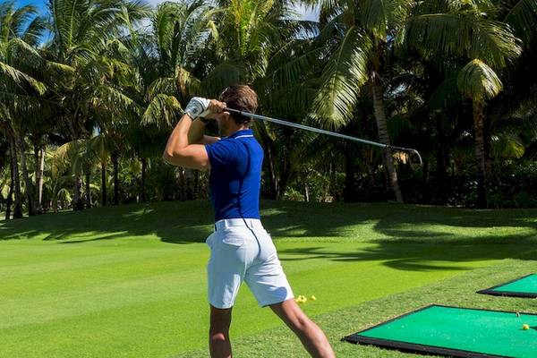 Golfspieler im Dinarobin Beachcomber Golf Resort & Spa auf einem Golfplatz mit Palmen im Hintergrund.