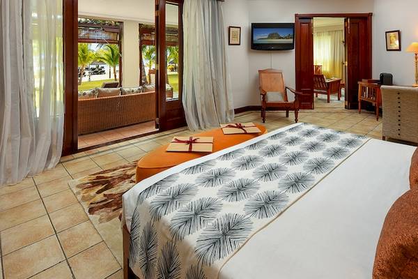 Hotelzimmer im Dinarobin Beachcomber Golf Resort & Spa mit Bett, Couch, Tisch und Ausblick auf den Strand.