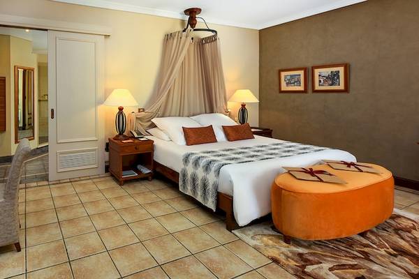Hotelzimmer im Dinarobin Beachcomber Golf Resort & Spa mit Bett, Schreibtisch, Stuhl und Lampe.