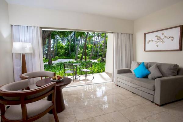 Wohnzimmer im Impressive Premium Punta Cana Hotel mit Blick auf die Außenlandschaft.