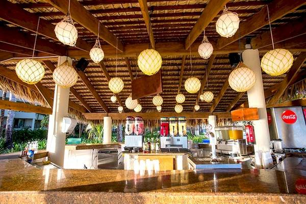 Bar im Impressive Premium Punta Cana Hotel mit tropischen Lampen und Getränkeautomaten.