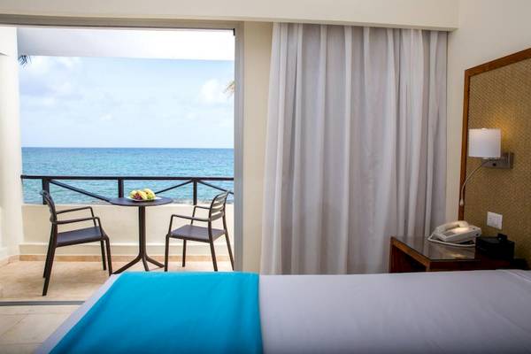 Zimmer mit Meerblick im Impressive Premium Punta Cana Hotel mit Balkon, Tisch, Stühlen und Telefon.