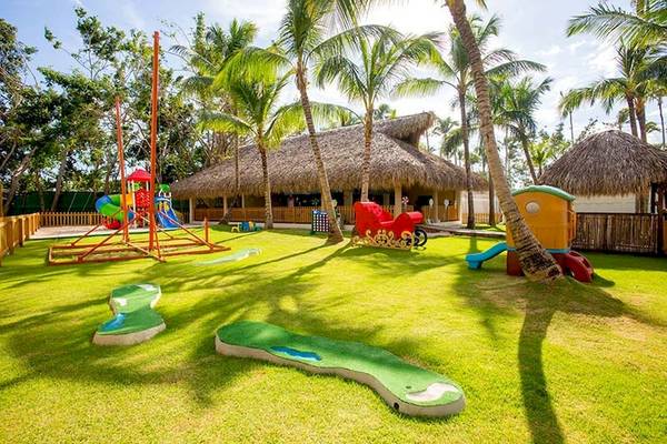 Kinderspielplatz im Impressive Premium Punta Cana mit bunten Spielgeräten und Palmen.