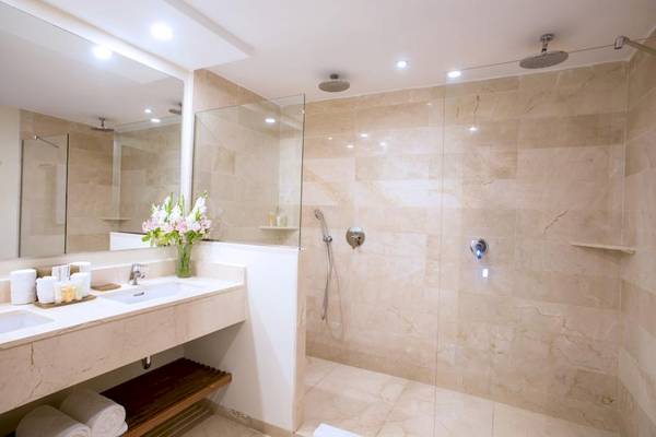 Luxuriöses Badezimmer im Impressive Premium Punta Cana Hotel mit Marmorfliesen, großer Dusche und Doppelwaschbecken.