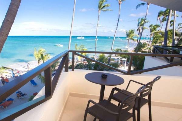 Ausblick vom Balkon des Impressive Premium Punta Cana auf Strand und Meer mit Palmen und Liegestühlen.