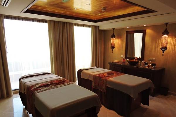 Massageraum im Marjan Island Resort & Spa mit zwei Massagetischen, Spiegel und orientalischen Lampen.