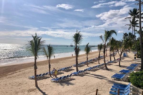 Strand am Impressive Premium Punta Cana Hotel mit blauen Liegestühlen und Palmen