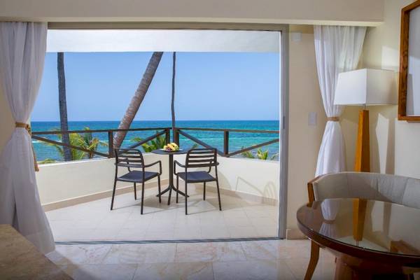 Blick aus dem Balkon des Impressive Premium Hotel in Punta Cana auf das Meer und Palmen.
