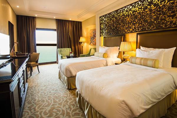 Doppelzimmer im Marjan Island Resort & Spa mit zwei Betten, Schreibtisch und Blick auf das Meer.
