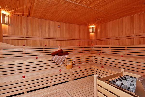 Innenansicht der Sauna im Botanik Platinum Hotel mit Holzbänken, Kerzen und Handtuch.