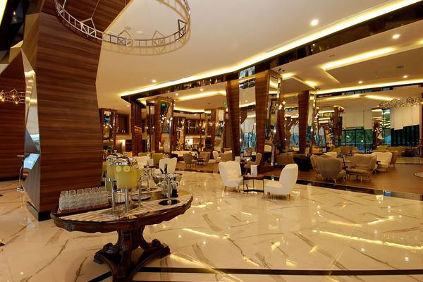 Lobby des Botanik Platinum Hotels mit weißen Stühlen und Marmorboden.