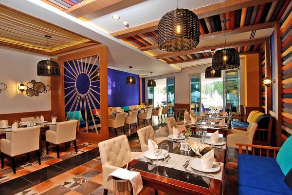 Innenansicht des Restaurants im Botanik Platinum Hotel mit bunten Wänden, Tischdecken und Hängelampen.