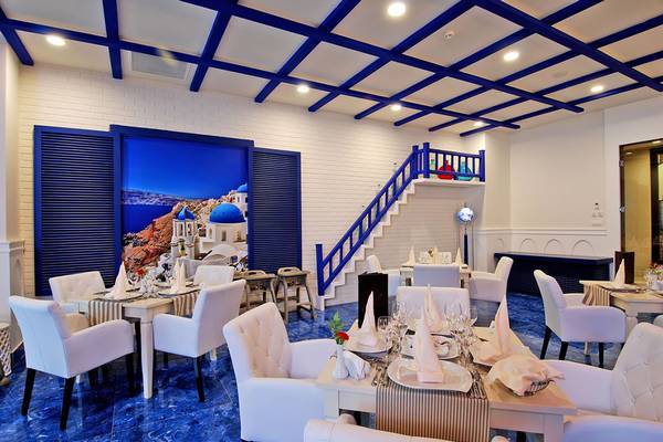 Innenbereich des Botanik Platinum Restaurants mit blauen Fliesen und weißen Möbeln.