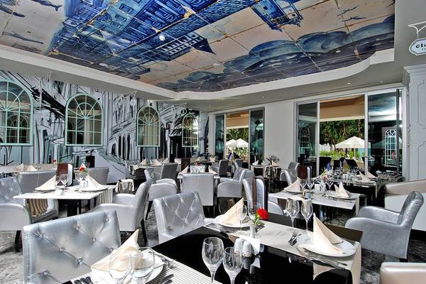 Innenansicht des Restaurants Botanik Platinum mit blauem Himmel-Design an der Decke und weißen Möbeln.