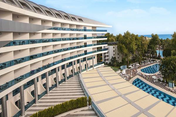 Außenansicht des Botanik Platinum Hotels mit Swimmingpools und Blick auf das Meer.