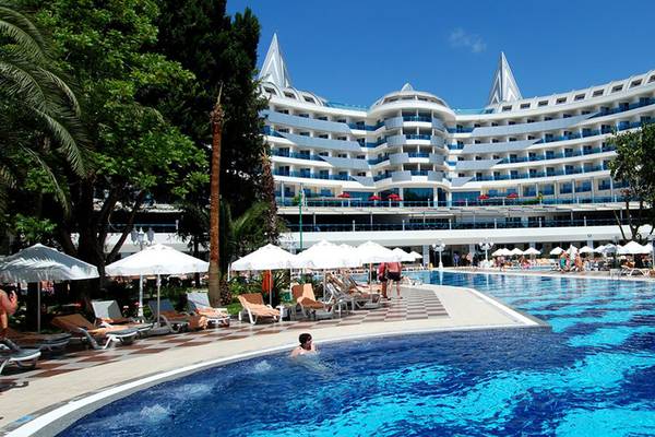 Ein großes Hotel namens Botanik Platinum mit einem großen Swimmingpool und vielen Liegestühlen.