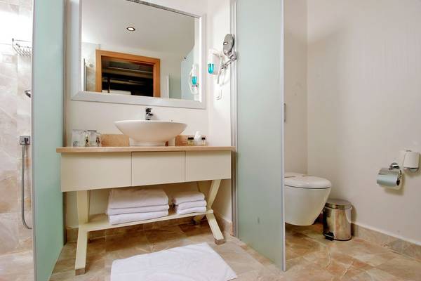 Badezimmer des Botanik Platinum Hotels mit Waschbecken, Spiegel und Toilette.