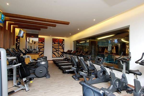 Fitnessstudio im Botanik Platinum Hotel mit vielen Geräten und einer großen Glaswand.