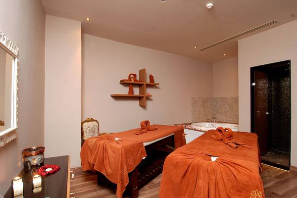 Spa-Raum im Botanik Platinum Hotel mit zwei Massagetischen, Whirlpool und Holzboden.
