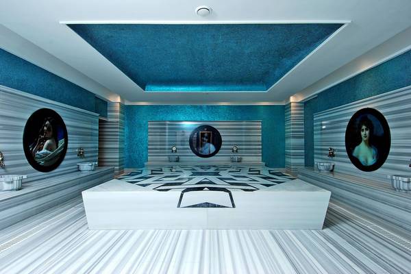 Ein Badezimmer im Botanik Platinum Hotel mit blauen Wänden, einer weißen Badewanne und Marmorboden.