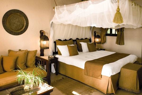 Schlafzimmer im Breezes Beach Club & Spa Zanzibar mit Moskitonetz, Bett, Couch und Pflanzen