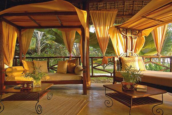 Loungebereich im Breezes Beach Club & Spa Zanzibar mit zwei Betten, Tischen und Pflanzen.