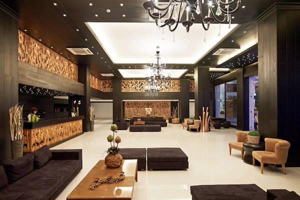 Lobby des Mitsis Faliraki Beach Hotel & Spa mit modernem Design, dunklen Möbeln und weißen Böden.