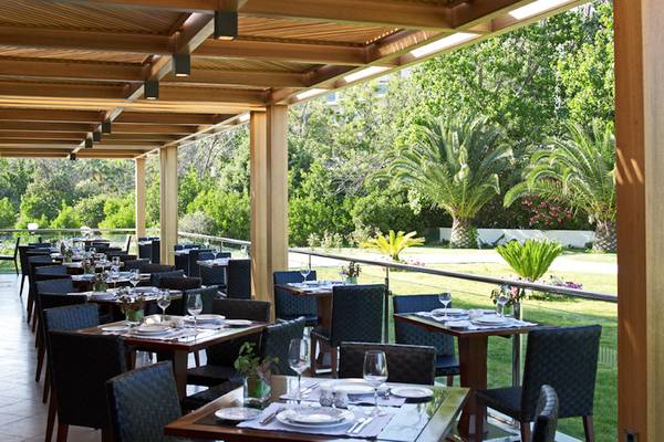 Außenbereich des Mitsis Faliraki Beach Hotel & Spa Restaurants mit Tischen und Stühlen unter einem Dach.