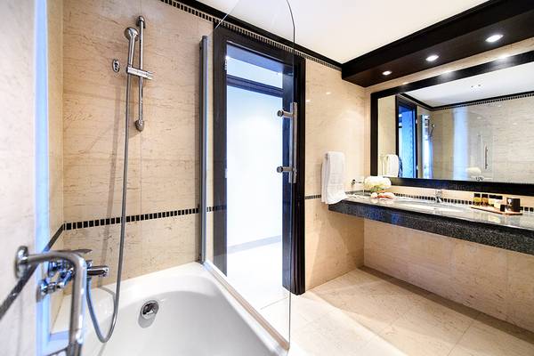 Badezimmer im Mitsis Faliraki Beach Hotel & Spa mit Badewanne, Glastür, Spiegel und Waschbecken