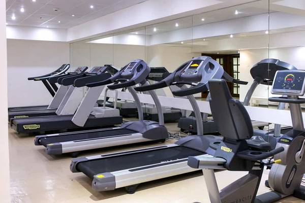 Fitnessstudio im Golden Bay Beach Hotel mit mehreren schwarzen und grauen Laufbändern.